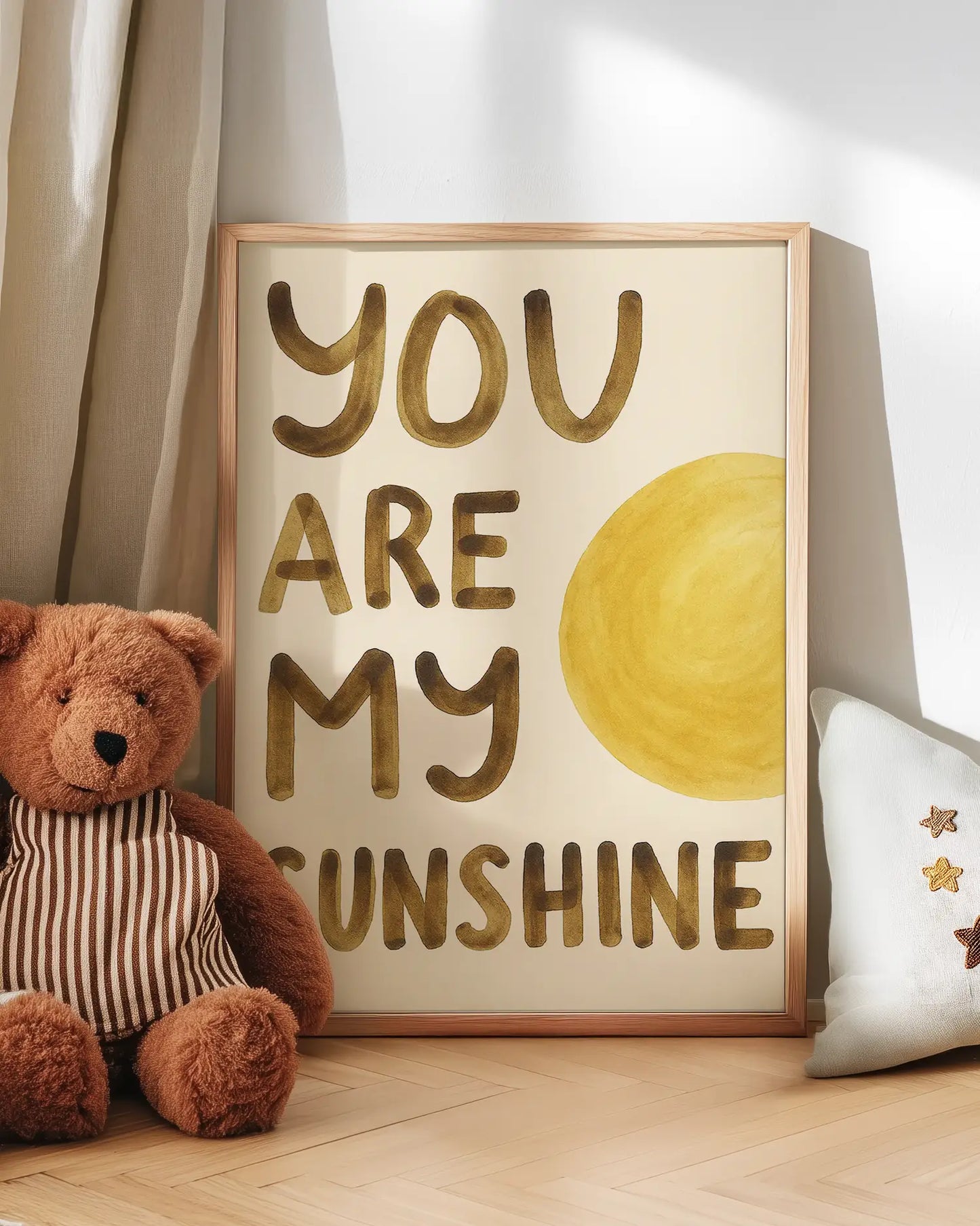 Artwork with 'You are my sunshine' text and a teddy bear on a wooden floor.