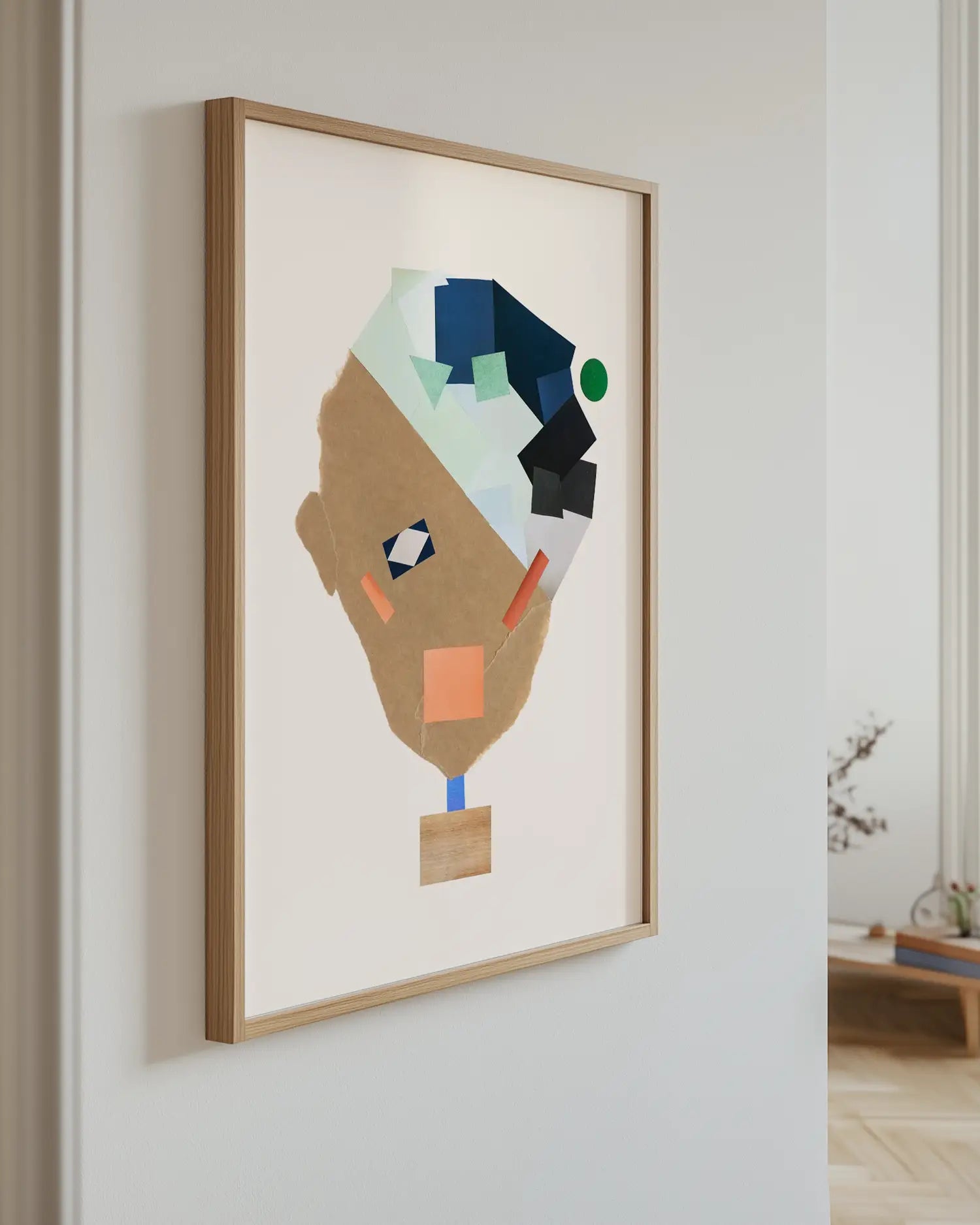 Abstract art piece of a collage face in a wooden frame on a white wall