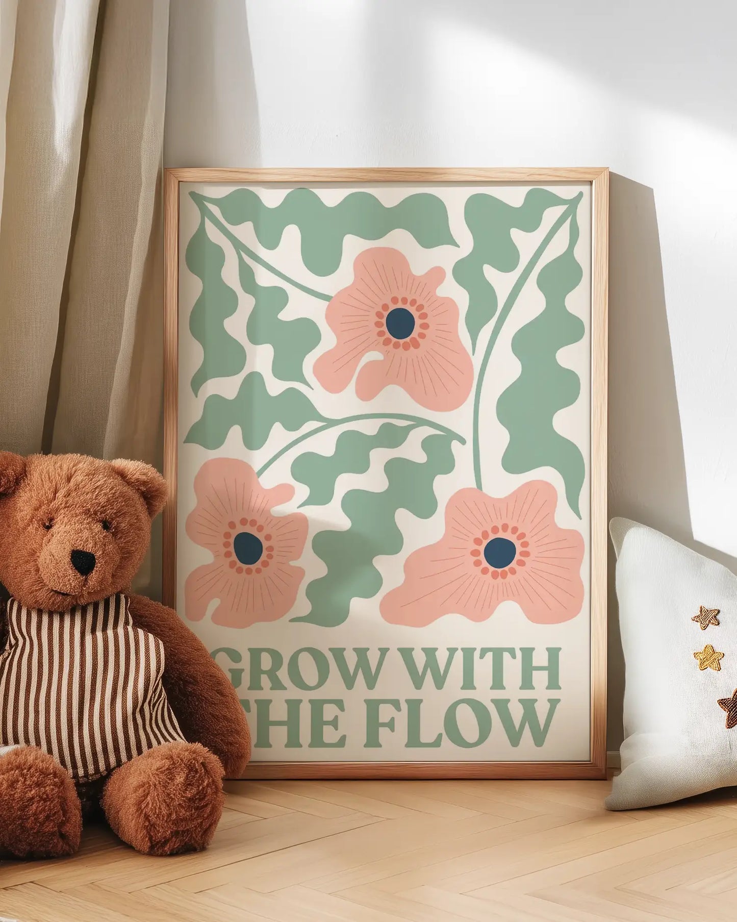 Floral artwork with 'Grow with the Flow' text, teddy bear, and pillow on a wooden floor.