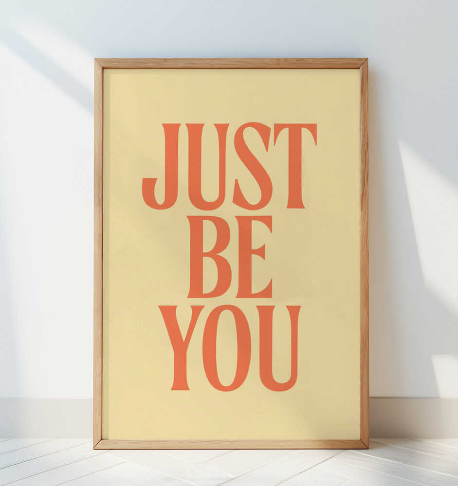 Framed nursery poster with 'JUST BE YOU' text in orange on a light yellow background