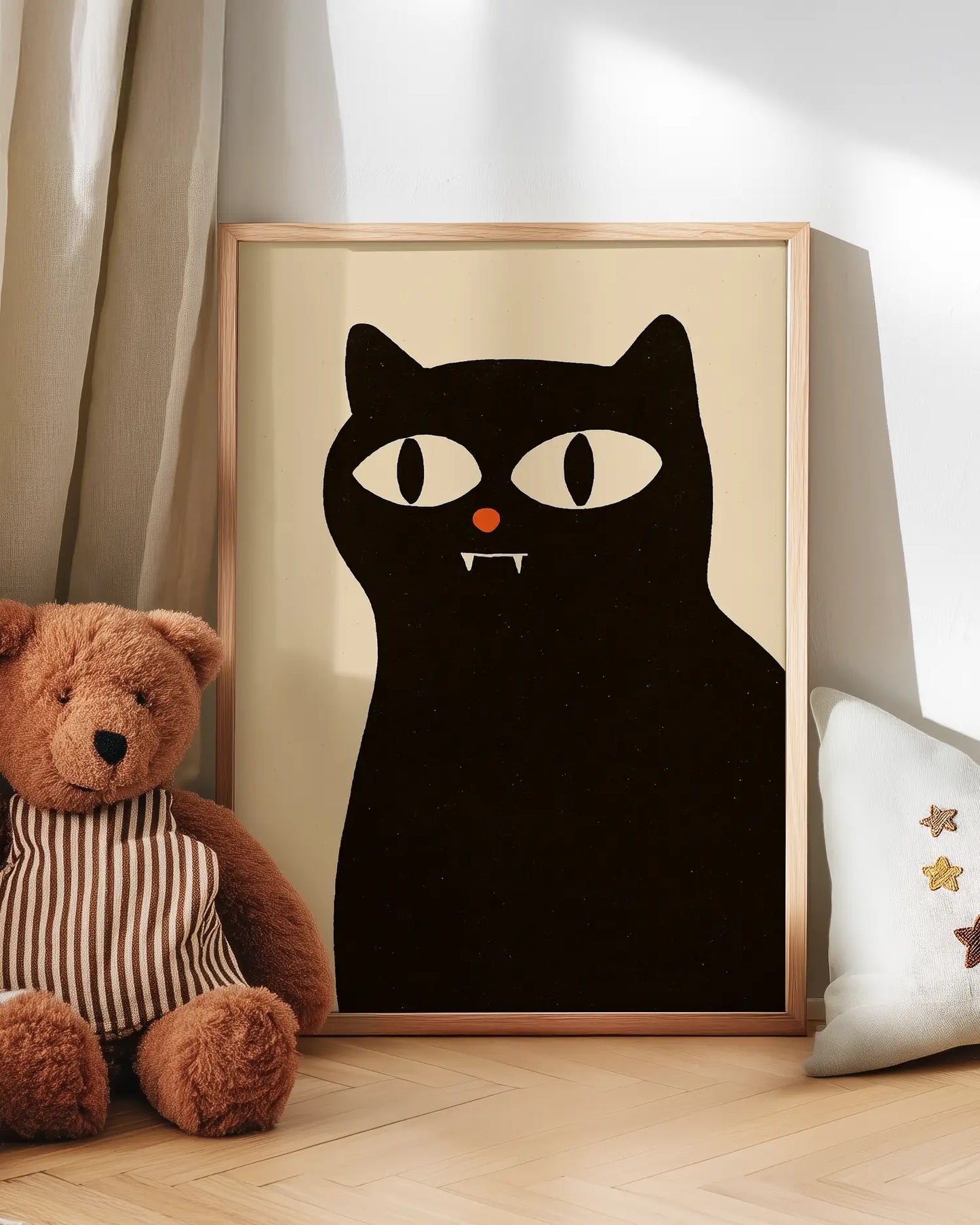 Framed poster of a black vampire cat with a teddy bear and decorative pillow on a wooden surface.