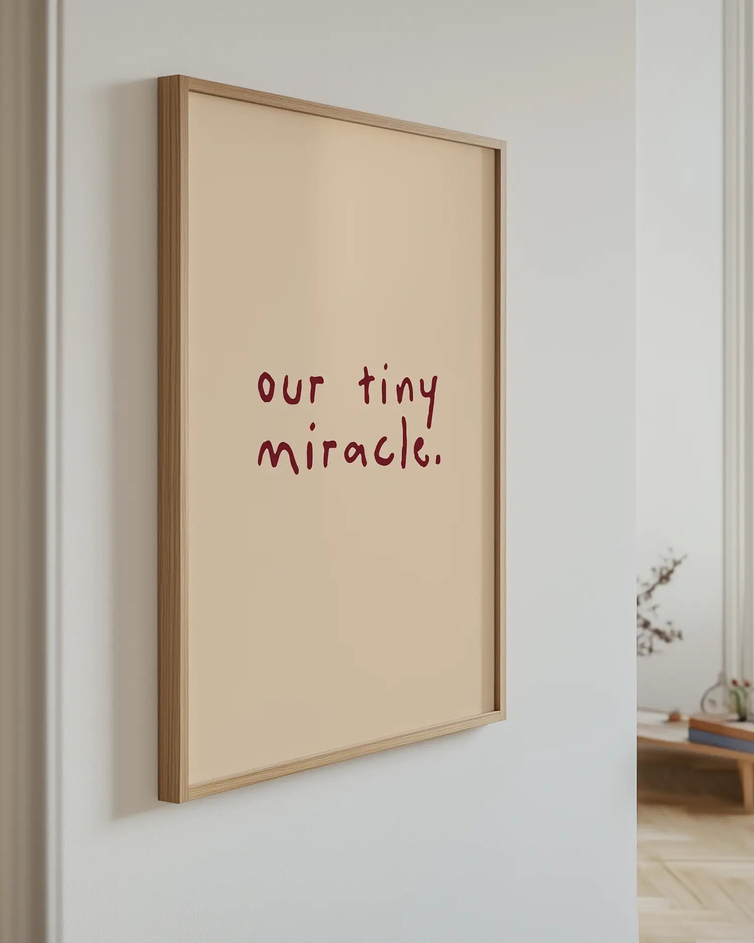 Framed artwork with 'our tiny miracle.' text on a white wall.