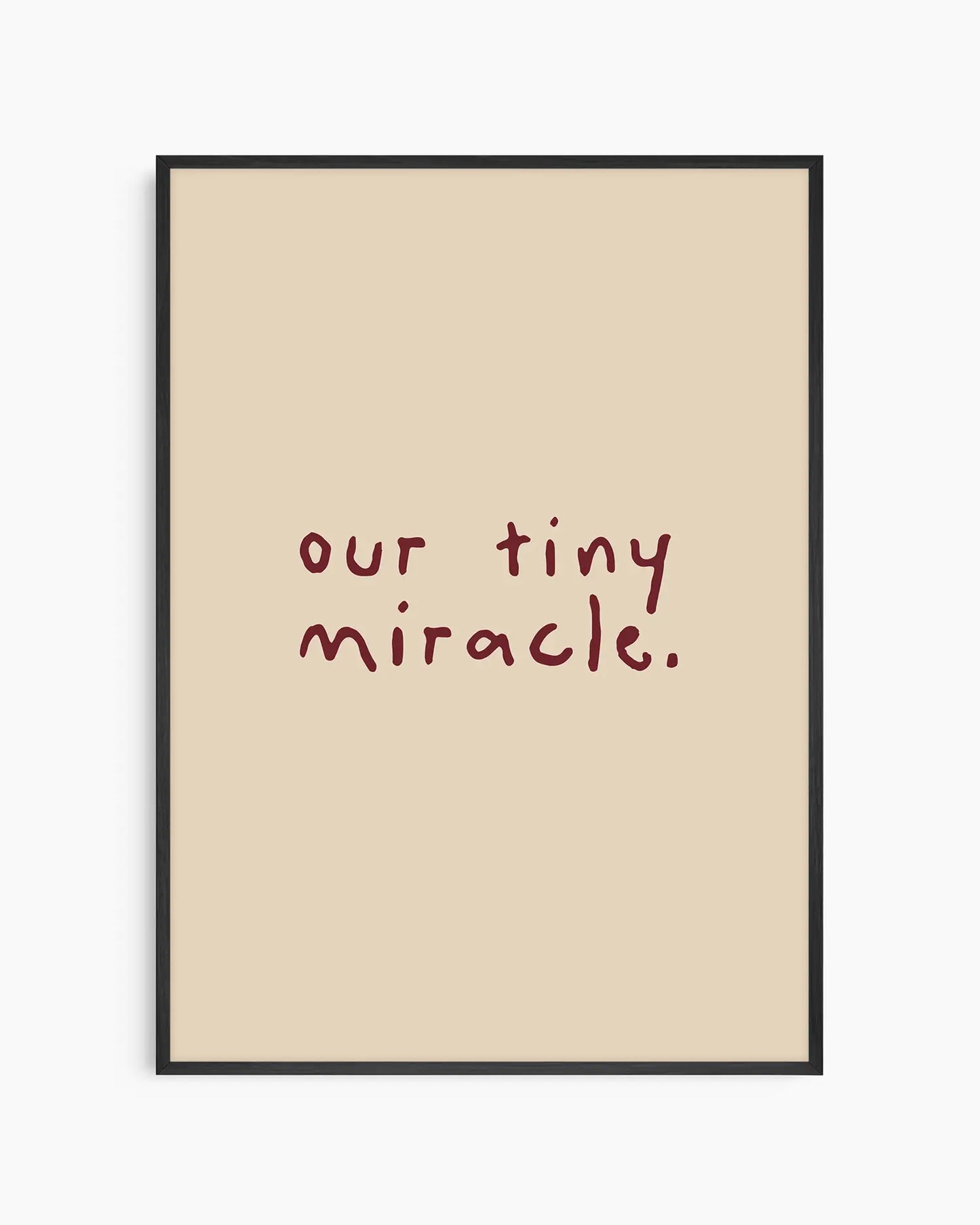 Beige nursery poster with 'our tiny miracle.' text in brown framed in a black frame.