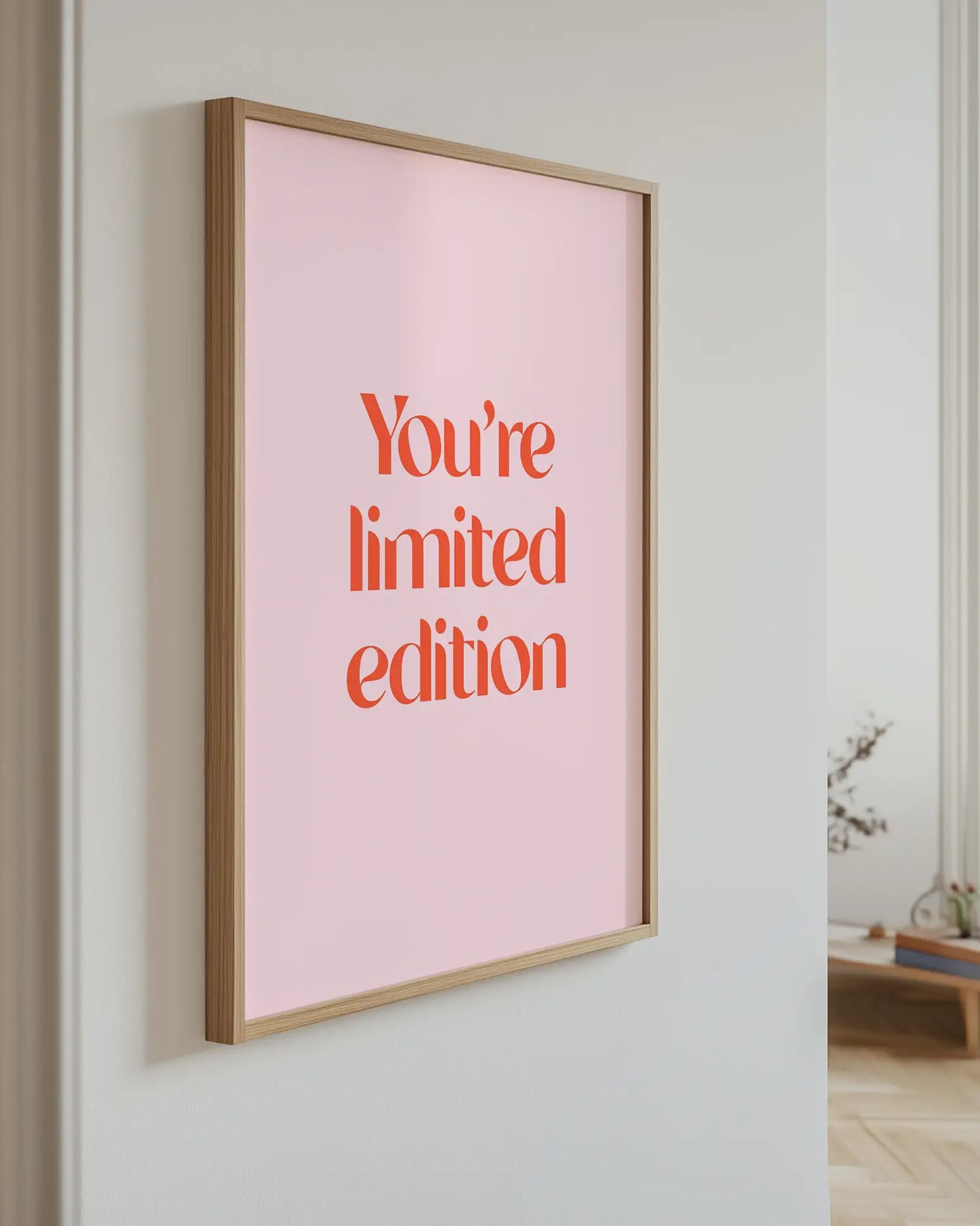 Artwork with 'You're limited edition' text on a pink background, mounted on a wall.