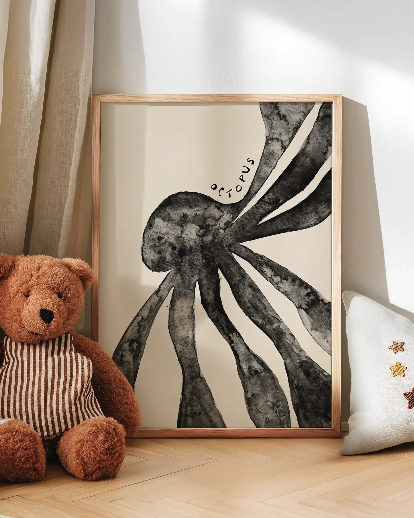 Framed black and white octopus art print on a wall with a teddy bear and decorative pillow.