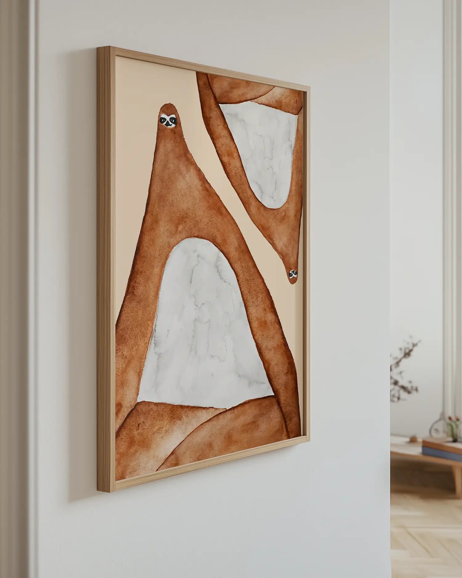Art piece with two lazy sloths in brown and beige tones on a white wall