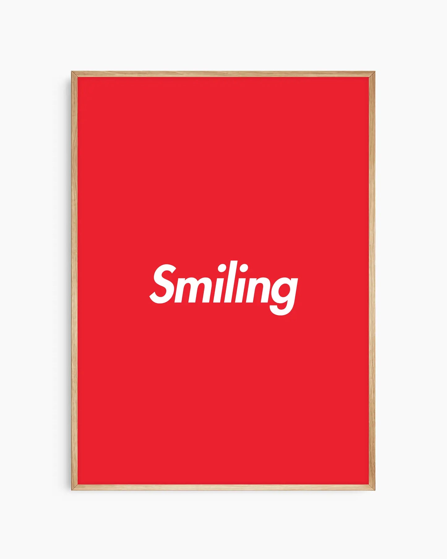 Red poster with 'Smiling' written in white, inserted in an oak frame.