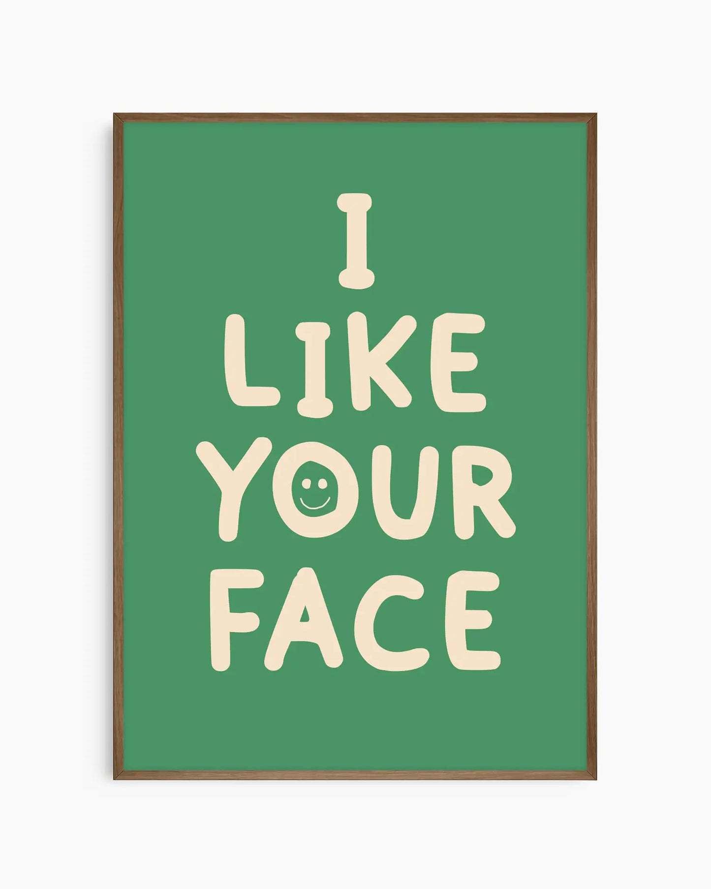 Green nursery poster with the text 'I like your face' written in beige, framed in a dark oak frame.