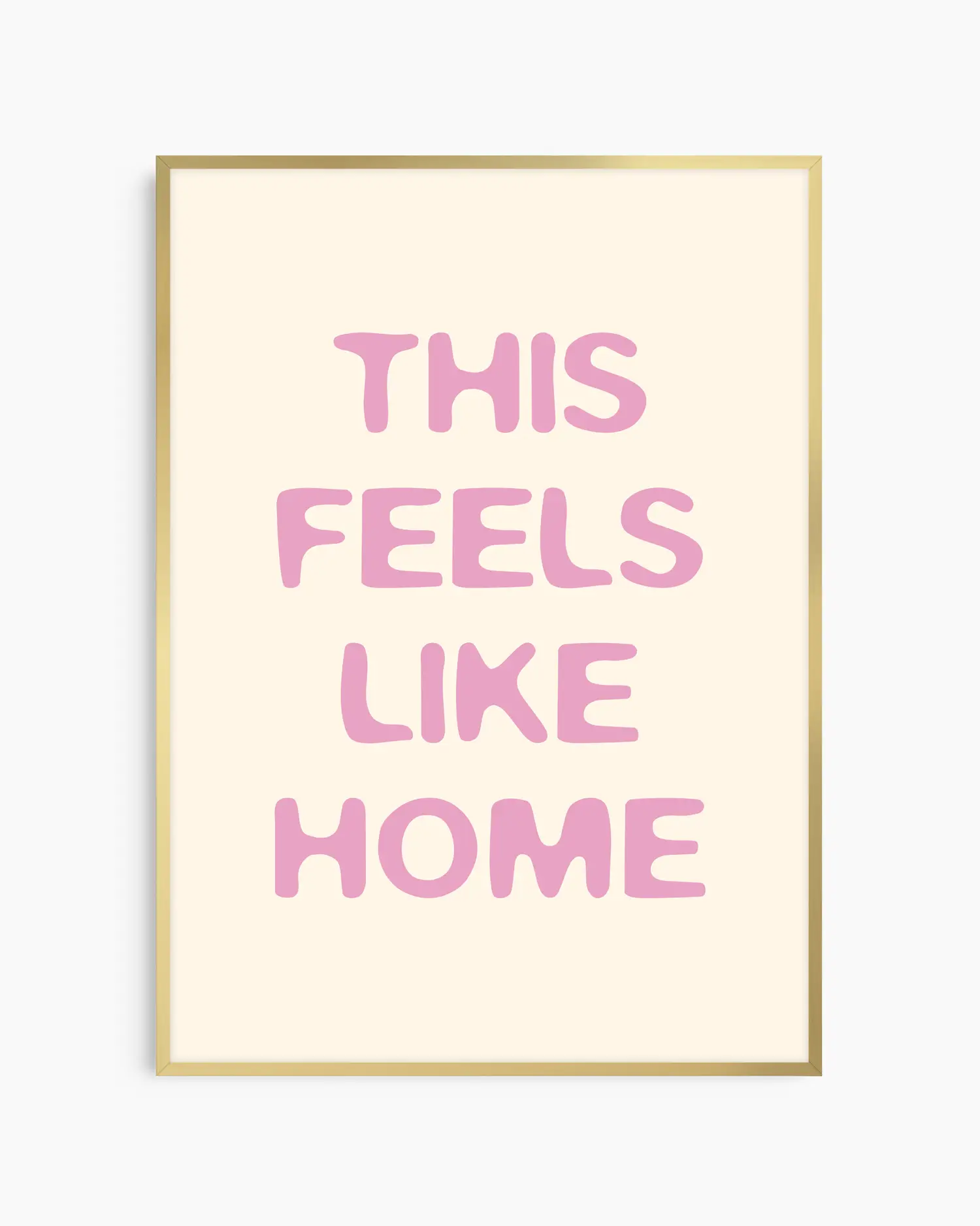 Nursery poster with the text 'This feels like home' written in pink on a beige background, framed in a gold frame