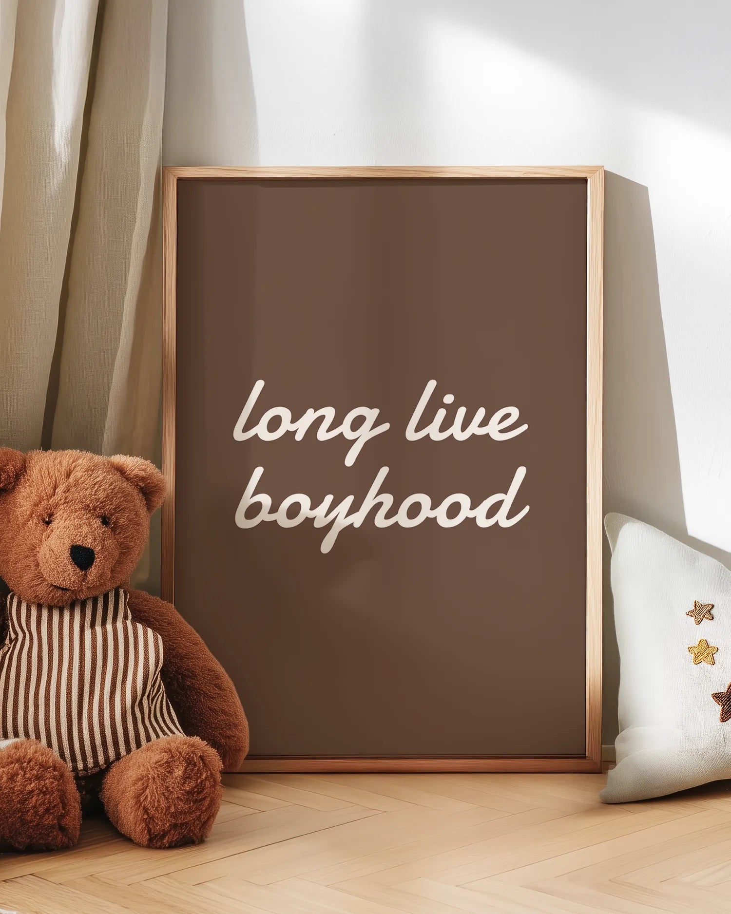 Framed artwork with 'long live boyhood' text next to a teddy bear on a wooden floor.